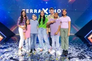 "Terra X-Show Kids"-Moderatorin Jess Schöne (M.) posiert mit ihren Gästen: Musiker Isaak (3.v.r.) und Foodinfluencerin Sally (1.v.l.), den Freundeteams Pearla (r.) und Jayden (2.v.r.) sowie Mia (2.v.l.) und Paolo (3.v.l.).