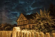 Nächtliches Fachwerkhaus mit Vorgarten.