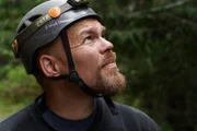 Jason Storie looking into the woods, with caving gear helmet on. (National Geographic/Jessica Burgess)