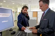 Abgelenkt unterschreibt Pipo (Adam Bousdoukos, li.) das Formular, das Bernd (Johannes Suhm) ihm vorlegt. Dummerweise ohne genauer auf den Text zu schauen...
