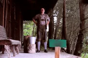 Bürgermeister Schattenhofer (Werner Rom) übt verbissen Zwetschgenkernweitspucken, um endlich Xaver darin zu schlagen.
