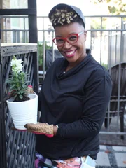 Mary poses with a plotted plant.
