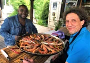 Raúls (r.) Paella auf offenem Feuer gekocht.