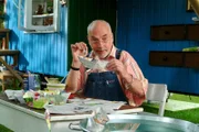 Damit die Papierboote wasserfest werden, streicht Peter (Peter Lustig) sie mit Leim ein.