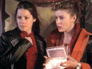 Phoebe (Alyssa Milano, r.) und Piper (Holly Marie Combs, l.) öffnen die Box, die die sieben Todsünden in Form kleiner Kugeln enthält.