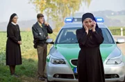 Schwester Hildegard (Andrea Sihler, l.) steht unter Schock, Mutter Oberin Theodora (Nina Hoger, r.) und Polizist Meier (Lars Weström, l.) rufen Verstärkung herbei.