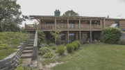 The back yard of the River Side Cabin is spacious with lots of native plants, as seen on Log Cabin Living.