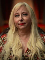 Die befragte Person, Rochelle Herman, sitzt auf einem Stuhl und schaut in die Kamera. Mittelaufnahme.