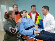 Paul Menke (Pierre Kiwitt, liegend) ist plötzlich mit starken Magenkrämpfen in seinem Fischgeschäft zusammengebrochen. Die Notärzte (Komparsen) bringen ihn in die Sachsenklinik. Maja Jäger (Ruth Moschner, links) lässt Paul keine Minute allein.