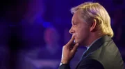 Chris Tarrant (Michael Sheen) stellt dem Teilnehmer auf dem heißen Stuhl die Quizfragen.