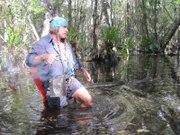 Cody Lundin walking through the swamp with a fire bucket.
