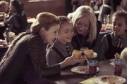 Frau Galle (Kacey Ainsworth, l.) und Agatha Graustein (Clare Higgins, r.) wollen Felicitas (Dagny Rollins) zu einem Törtchen verführen. Diese drei Törtchen sind verwandelte Mitschülerinnen.