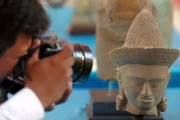 Ein kambodschanischer Fotograf fotografiert einen Steinkopf während einer Übergabezeremonie von sieben Khmer-Artefakten aus den USA an die kambodschanische Regierung am 18. Juli 2010 im Nationalmuseum in Phnom Penh. Burns ist wegen Veranstaltungen zum 60. Jahrestag in Phnom Penh der Beziehungen zwischen Kambodscha und den Vereinigten Staaten, bevor er nach Indonesien aufbricht, mit dem Präsident Barack Obama engere Beziehungen gesucht hat.