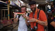 Zauberer Kalibo und Entertainment-Manager Alex essen Wassermelone auf dem Markt in Cartagena, Kolumbien