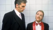 Nikola (Mariele Millowitsch, r.) versucht Dr. Schmidt (Walter Sittler) in der Herrentoilette durch bissige Bemerkungen abzuschrecken, damit ihre Verkleidung nicht auffliegt...
