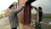 Halligbewohner bereitet Schotten seines Hauses auf Sturm vor.