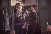 Esther (Jenny Richardson, l.) und Mildred (Bella Ramsey, r.) sind durch einen Freundschaftszauber an ihren Unterarmen fest miteinander verbunden. Nun müssen sie alles gemeinsam machen. Der Zauber löst sich erst auf, wenn sie nett miteinander umgehen.