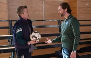Hannes Seela (André Dietz, li.) fordert vehement einen Freistoß in einem Trainingsspiel für seinen Sohn. Trainer David Ziegler (Matthias Schloo, re.) findet seine Reaktion völlig übertrieben und fordert ihn auf, die Turnhalle zu verlassen.