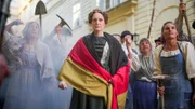 Caroline von Perin als mutige Heldin: Eine metaphorische Darstellung ihres Kampfes um Wien. Umgeben von Handwerkerinnen und Studenten steht sie im Mittelpunkt – an ihrer Seite Alfred Julius Becher.