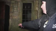 Der Mann zeigt auf die dunkle Tür.