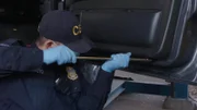 CBP-Beamter Soto verwendet eine Metallstange, um die Autotür eines Verdächtigen auf weitere Schmuggelware zu untersuchen (National Geographic).