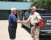 Texas Fish and Game Warden Benny Richards shaking hands with Texas resident Mr. Snedeker after removing a raccoon from his property.