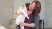 Lola holding Jimmy the cat inside the home.