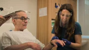 MId shot of Chris on Clinic bed as Dr Emma inspects the Psoriasis on his arm