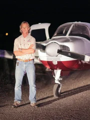 Mike standing in front of a plane at night.