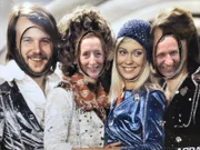 Entertainerin Kiona und Kreuzfahrtdirektor Jöhrn Hofer beim Besuch des ABBA-Museums, wo sie ihre Köpfe durch ein ABBA Plakat stecken.