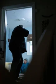 Ein Mann bedroht eine verängstigte Frau, die auf dem Boden sitzt.