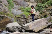 Mariela überquert den Bach am Wasserfall.