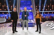 Moderator Jörg Pilawa (M.) mit den Kandidat:innen des Teams "TV-Klinik": Dem Schauspieler Thomas Rühmann (l.) und der Schauspielerin Arzu Bazman (r.).