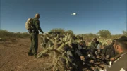 Nogales, AZ: An agent signaling to a helicopter in the air, while a group of apprehended men sit on the ground. Helicopters have been beneficial in conducting high speed chases.