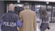 Der Polizist bringt den verhafteten Passagier zum Polizeiauto.