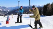 Checker Tobi hilft Chris bei der Arbeit im Snowpark. Sie bauen zusammen eine große Schanze aus Schnee.