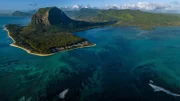 Der 556 Meter hohe Le Morne im Südwesten von Mauritius ist das Wahrzeichen der Insel. Eine weitere Attraktion ist die optische Täuschung am Fuße des Felsens: Das Korallenriff und Sandwirbel lassen es so aussehen, als ob ein riesiger Wasserfall zum Grund des Indischen Ozeans stürzt.