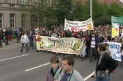 Demonstration gegen die Olympischen Spiele in den 1990er Jahren: Der eigentliche Geist des sportlichen Wettbewerbs wird durch wirtschaftliche und politische Interessen in den Hintergrund gedrängt.