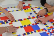 Alle helfen mit, die Klebestreifen in komplizierter Ordnung anzubringen.