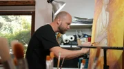 Tim Ernst in seinem Atelier, während er die Kopie des Werkes „Selbstbildnis am 6.Hochzeitstag“ von Paula Modersohn- Becker anfertigt.