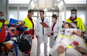 Nikki Schönau (Lena Meckel, re. liegend) und Hauke Friedrich (Oliver Konietzny, li. liegend) sind mit dem E-Roller auf dem Weg zum Standesamt verunglückt. Notarzt Dr. Lorenz (Markus Neumann, hi. li.) klärt Dr. Maria Weber (Annett Renneberg, hi. re.) und Dr. Philipp Brentano (Thomas Koch, hi. mi.) über die festgestellten Verletzungen auf.
