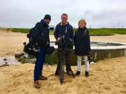 Autorin Barbara Lueg mit Kameramann Thorsten Eifler (M.) und Assistent Louis Münzhuber (l.) am Stadtstrand Nauthólsvik in Reykjavík.