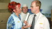 Rita (Gaby Köster) weiht Schumann (Lutz Herkenrath, r.) und Bernie (Georg Alfred Wittner) in ihren Plan ein, wie sie verhindern können, dass Gisi einen Nervenzusammenbruch erleidet: kein Wort über Puppen und Sexspielzeug...