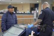 Der CBP-Aufsichtsbeamte Pacheco befragt einen Passagier, während er dessen Habseligkeiten in Atlanta, Ga. durchsucht.