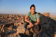 Albert Lin posiert für ein Porträt auf einem Felsen in der Wüste, während er eine Expedition tief in den Oman leitet, um nach Hinweisen zu suchen und das wahre Ausmaß und die Raffinesse einer verlorenen Wüstengesellschaft zu entdecken.