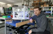 Erfinder Dimitri Benke aus Darmstadt sitzt neben seiner Erfindung, dem magnetischen Kühlsystem für Kühlschränke.