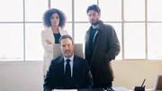 Sylvie (Stéfi Celma, l.), ihr Mann Luca (Lino Guanciale, r.) sowie dessen bester Freund Stefano (Fausto Sciarappa, M.) beraten das weitere Vorgehen in einem Büro der Werft.