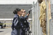 Cam (Tamara Taylor, l.) und Brennan (Emily Deschanel) untersuchen eine völlig verweste Leiche, die nach Myrrhe und Weihrauch riecht und am Zaun einer Fabrik hängt.