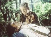 Laura (Melissa Gilbert, r.) muss den schwer verletzten Charles (Michael Landon, liegend) aus der Wildnis retten.