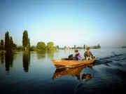 SWR-Kameramann im Boot eines Bodenseefischers. Im Hintergrund die Insel Reichenau.